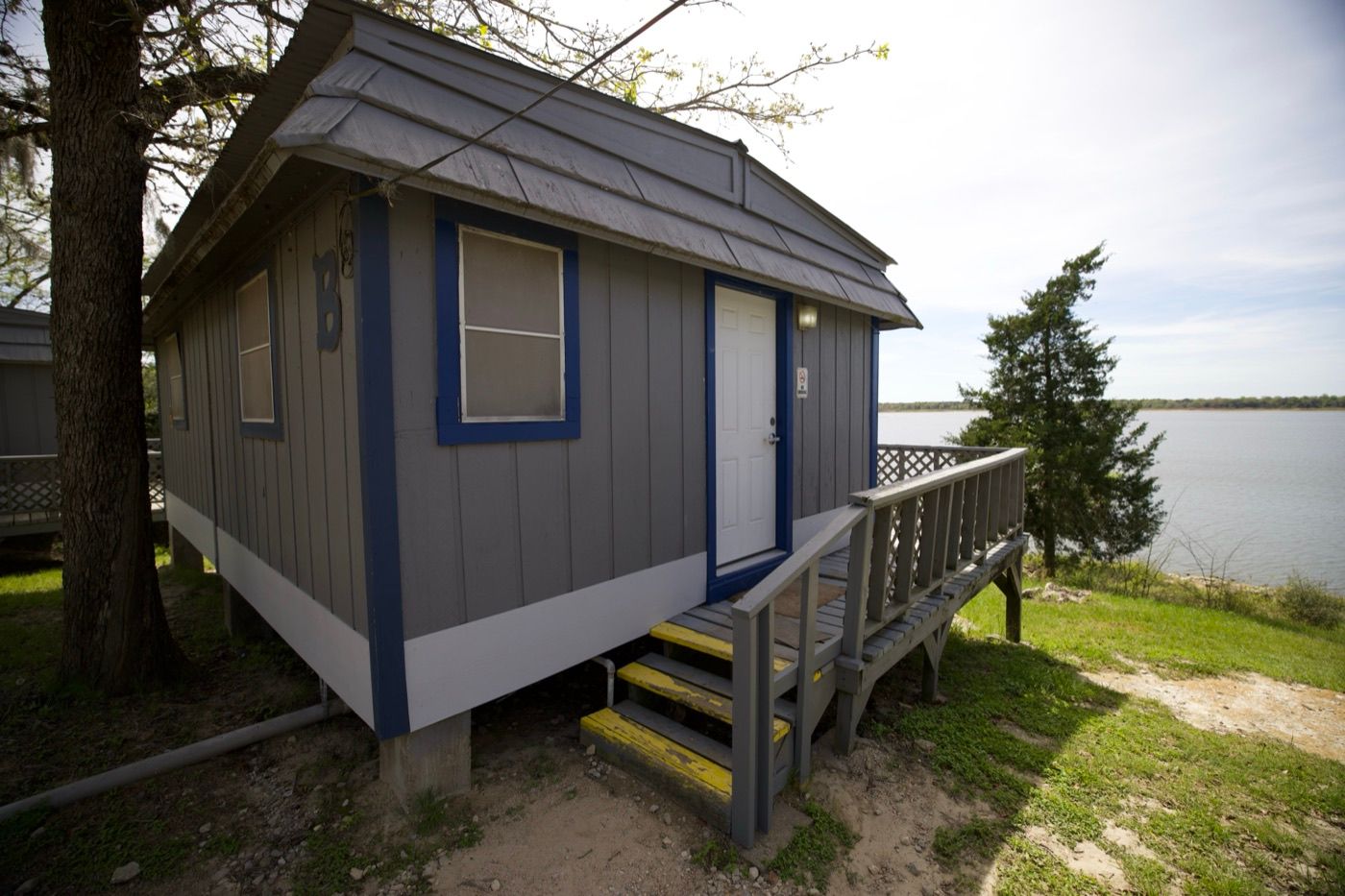A grey cabin with blue trim on the bluff, with Lake Somerville beyond.