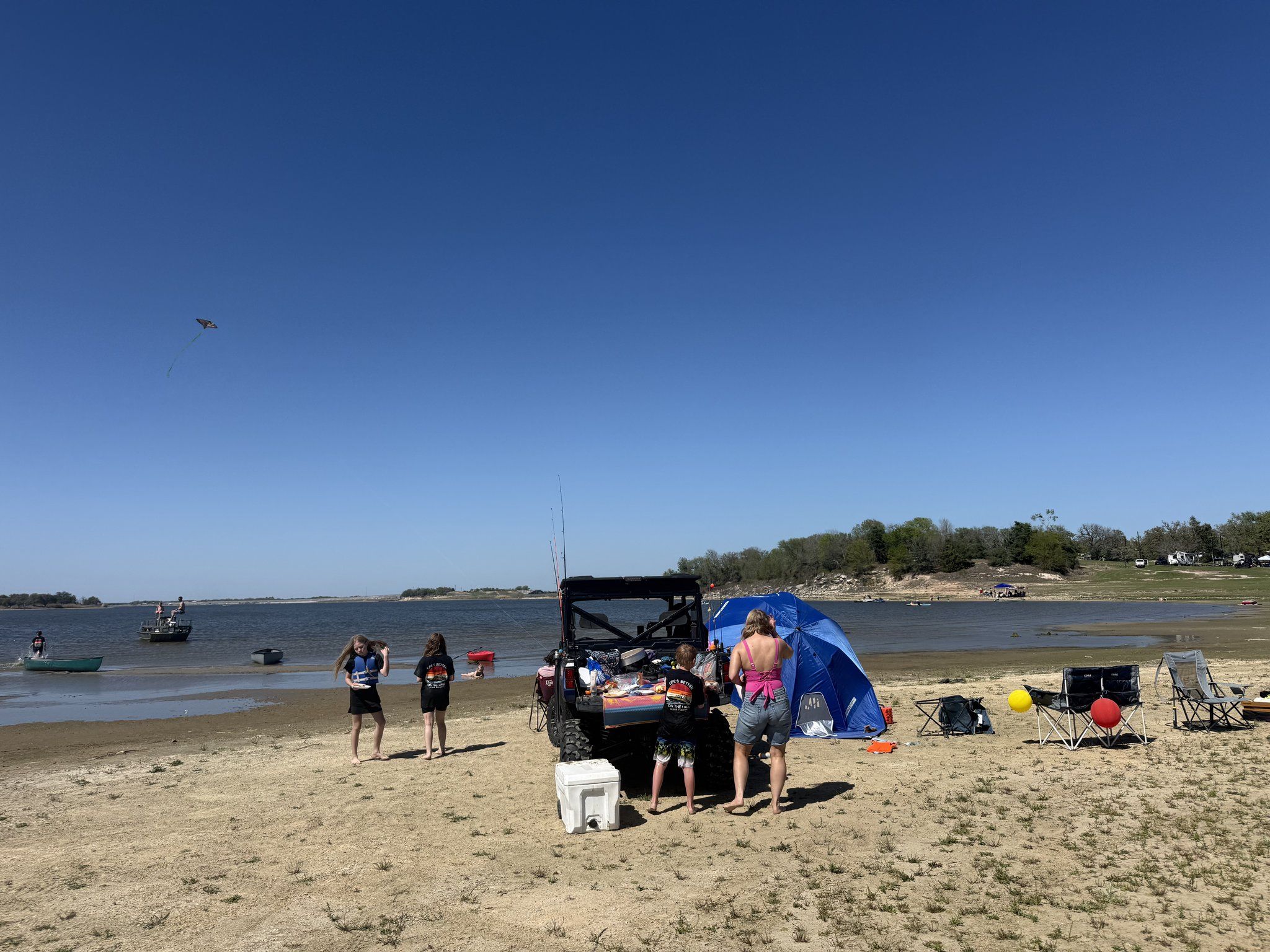Families set up on the sandbar beach with umbrellas and coolers beside Lake Somerville.