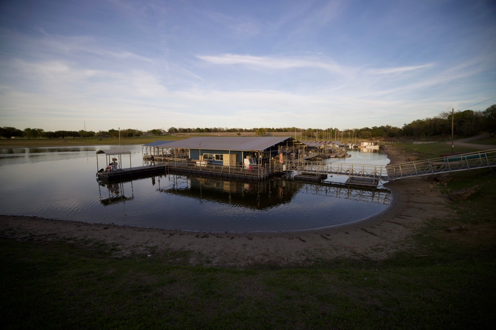 The floating marina building at dusk with the covered fuel dock on the left and the walkway leading back to the bank.