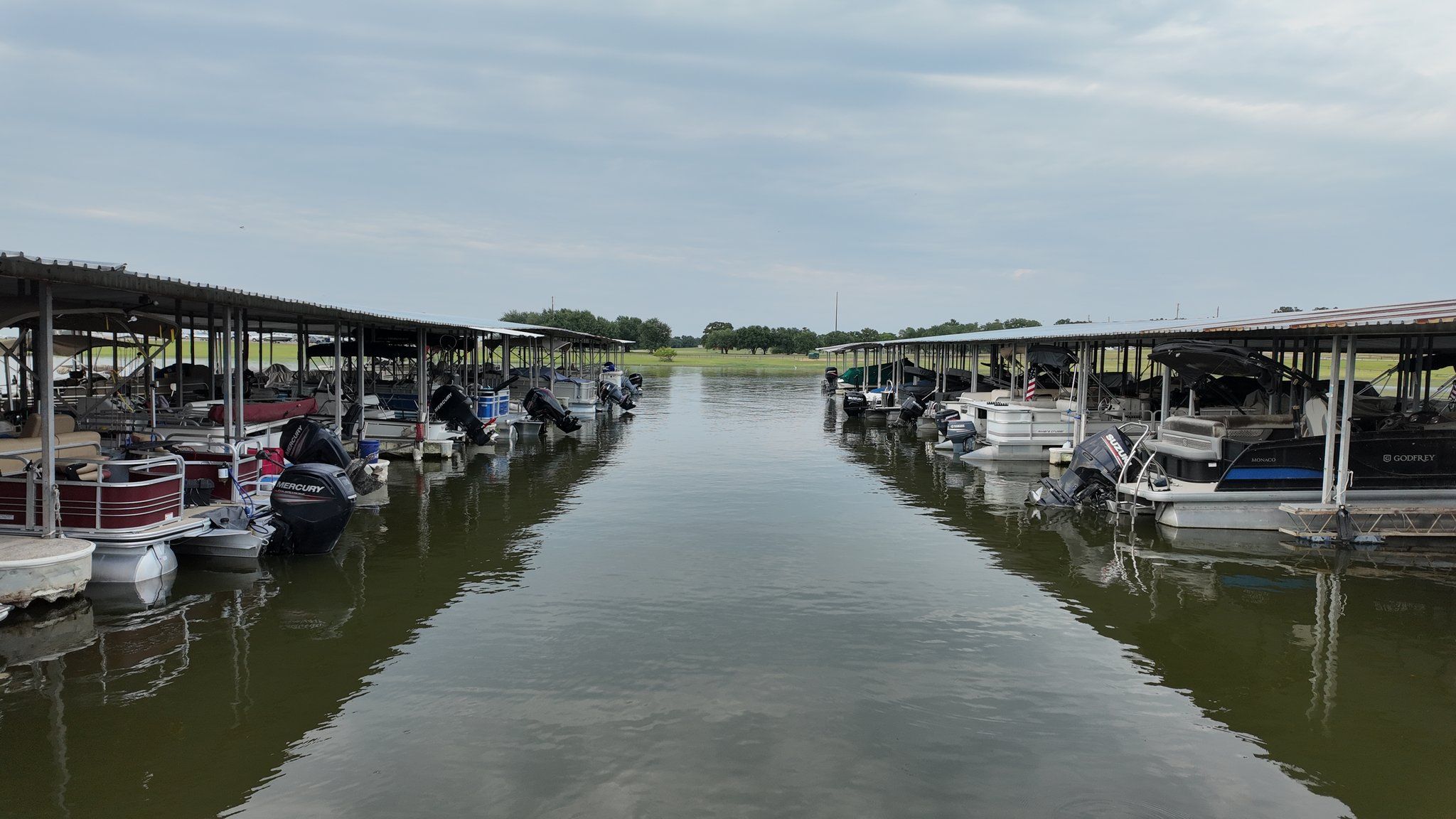 The fairway between two rows of covered boat slips, with pontoons and outboards moored on both sides.