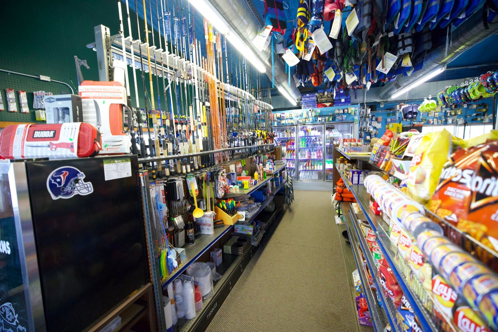 A marina store aisle stocked with tackle, snacks and coolers.
